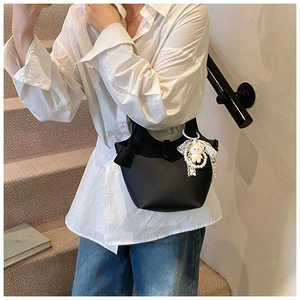 Detail of black bucket bag with lychee pattern leather and cute plush rabbit charm