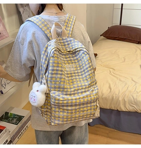 Detail of yellow and blue plaid backpack with a cute white bunny plush pendant for students