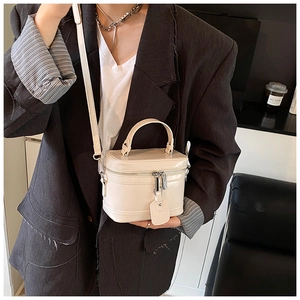 Sac seau chic crème en forme de boîte porté avec un blazer noir dans un décor moderne