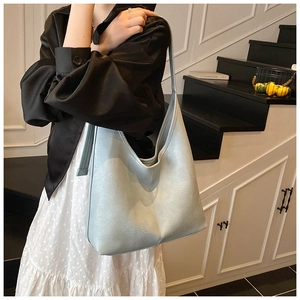Close-up of light blue textured leather tote bag with wide shoulder strap on model