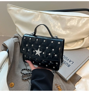 Detail of black quilted patent leather bag with silver rivets and diamond star ornament