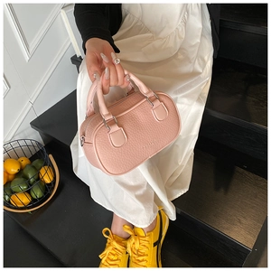 Detailed shot of a pink pebbled leather cylinder handbag with silver metal hardware