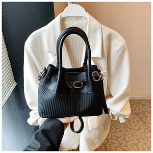 Detailed close-up of black leather bucket bag with woven texture and buckle accent