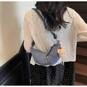Detail der blauen Jeans-Tasche mit geknotetem Schultergurt und Plüschbären-Anhänger