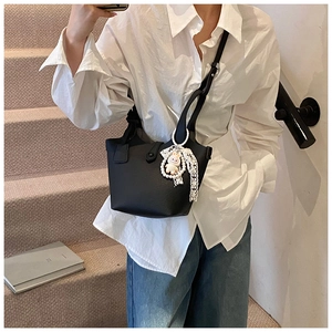 Detail of black pebbled leather bucket bag with pearl and rabbit charm on steps