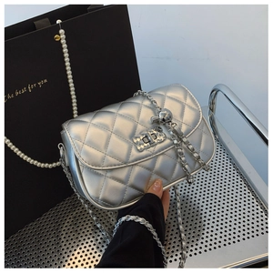 Detailed view of silver quilted lacquer bag with pearl chain and adjustable metal ball