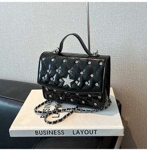 Detailed shot of black patent leather bag with quilted pattern and rhinestone star decoration
