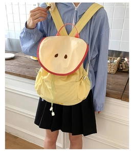 Detail of yellow nylon backpack featuring cartoon eye accents and vibrant colorful straps