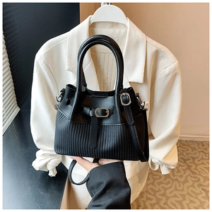 Detailed close-up of a black woven texture bucket bag with metal buckle and shoulder strap