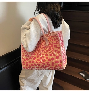 Outdoor shot of a pink leopard print tote bag being worn on a model's shoulder