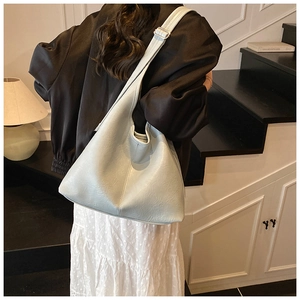 Detail of light blue-grey hobo bag with leather texture and silver buckle on adjustable strap