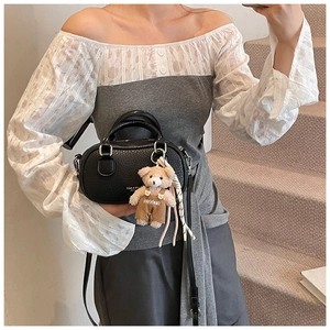 Close-up of black lychee leather bowling bag with cute teddy bear plush pendant