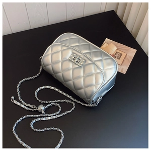 Close-up of silver quilted crossbody bag with metallic chain and turn-lock closure detail