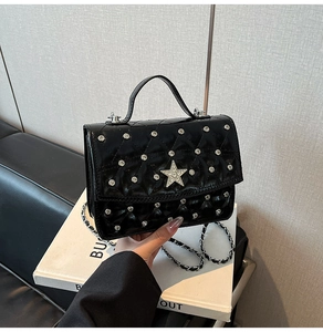 Close-up of quilted black patent leather handbag with a sparkling silver rhinestone star