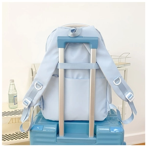 Détail du sac à dos bleu clair avec sangle de bagage et bretelles blanches respirantes
