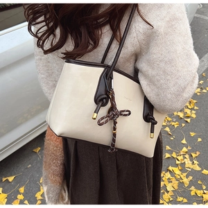 Dettaglio borsa tote retrò in pelle crema e marrone con ciondolo in corda intrecciata