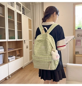 Detail of light green plaid backpack with a cute white rabbit plush charm on the side