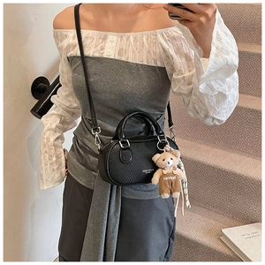 Mirror selfie showing black pebble leather bowling bag with cute teddy bear charm