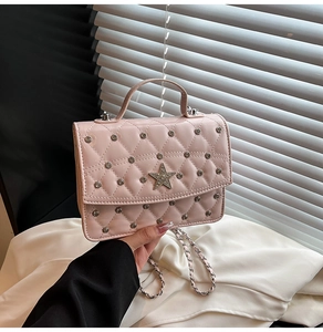 Detail view of pink quilted chain bag with silver studs and a shiny star emblem