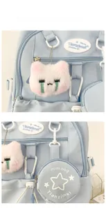 Détail du sac à dos bleu clair avec pendentif chat en peluche et mini porte-monnaie