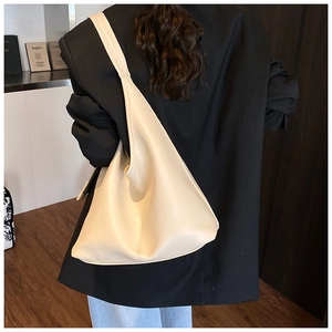 Rear 45-degree angle of a cream bucket bag worn over the shoulder showing soft PU texture