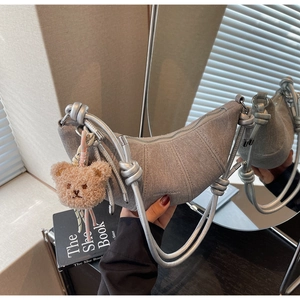 Details der silbernen Halbmondtasche mit Metallgurt und süßem Teddybär-Anhänger