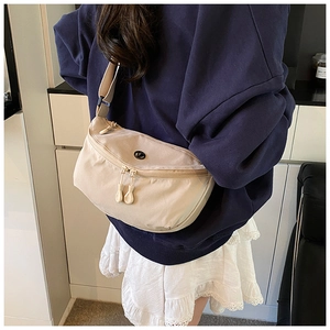 Close-up of beige nylon crescent bag featuring dual zippers and adjustable crossbody strap