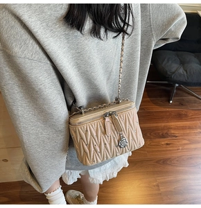 Detail of beige quilted mini crossbody bag with metal chain strap and rose charm