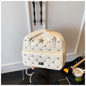 Close-up of beige quilted patent leather backpack with silver rivets and star emblem