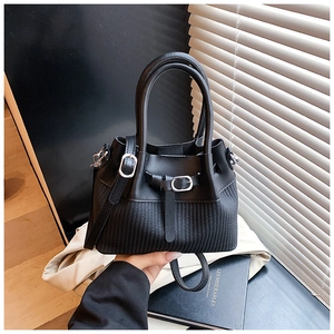 Detail of a black bucket bag showing the unique woven texture and smooth leather mix