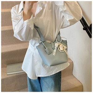 Detail of light blue bucket bag featuring a decorative pearl bunny and lace charm