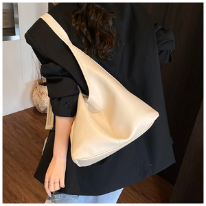 Detail of cream beige leather bucket bag worn by model over a black blazer