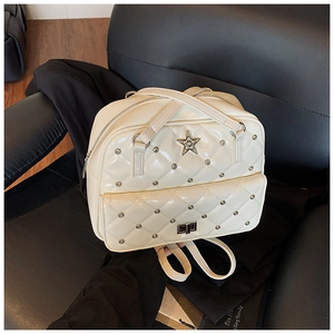 Detail shot of beige quilted backpack with star emblem and metal stud embellishments