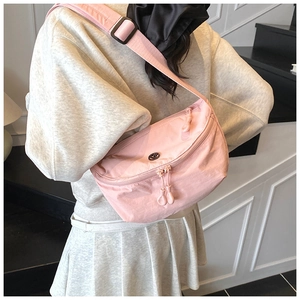 Pink nylon crescent crossbody bag shown from behind to display size and fit on a model