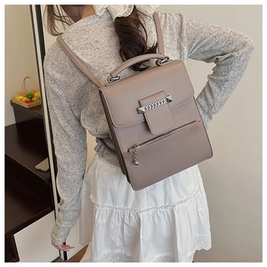 Detailansicht des taupefarbenen PU-Lederrucksacks mit Kette am Model in Wohnumgebung