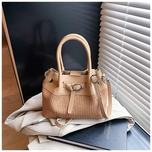Detailed view of beige woven bucket bag with buckle detail and silver hardware on neutral background
