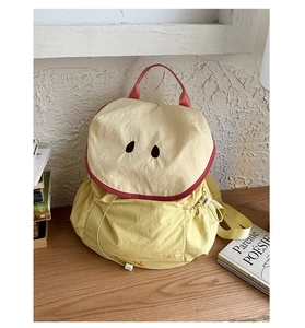 Detail of yellow apple shaped drawstring backpack with red piping and embroidery