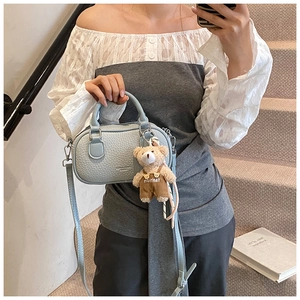 Detail of light blue pebble leather bowling bag with cute plush bear charm accessory