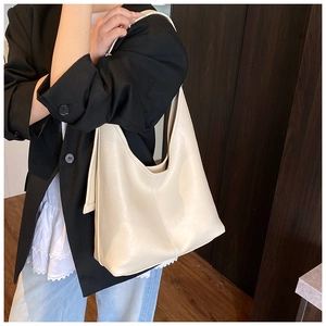 Detail of high-capacity cream leather tote bag featuring refined lychee texture and stitching