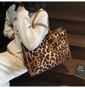Close-up of leopard print tote bag with brown handles on dark wooden steps