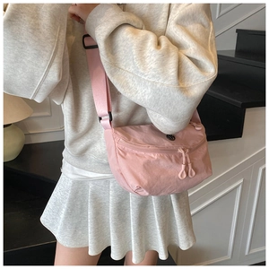 Detail of pink crossbody crescent bag with adjustable strap and double zipper closure