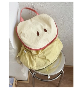 Detail of cute apple-shaped backpack with soft yellow canvas and pink trim for kids