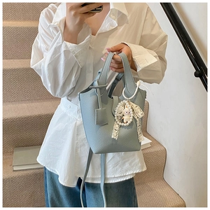 Detail of light blue leather bucket bag with white lace pearl rabbit charm on stairs