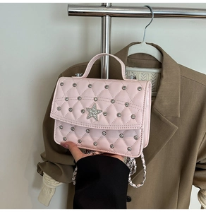 Pink quilted crossbody bag with silver studs and crystal star decoration in hand