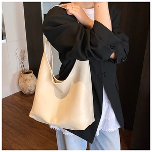 Minimalist beige PU leather bucket tote bag shown with model in professional business attire