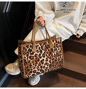 Close-up of a large leopard print tote bag with durable brown canvas handles and trim