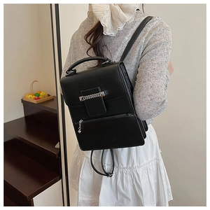 Detail eines schwarzen Lederrucksacks mit Silberkette, Nieten und rundem Metallreißverschluss
