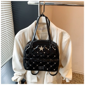 Detail of black quilted patent leather bag with silver studs and star emblem