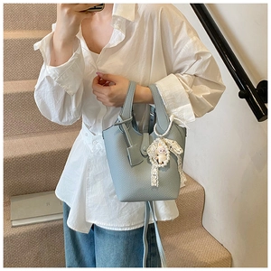 Light blue bucket bag with leather texture and cute sheep charm in a lifestyle setting