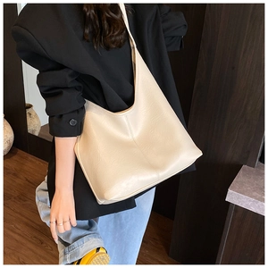 Close-up of off-white bucket bag with leather texture shown on model's shoulder